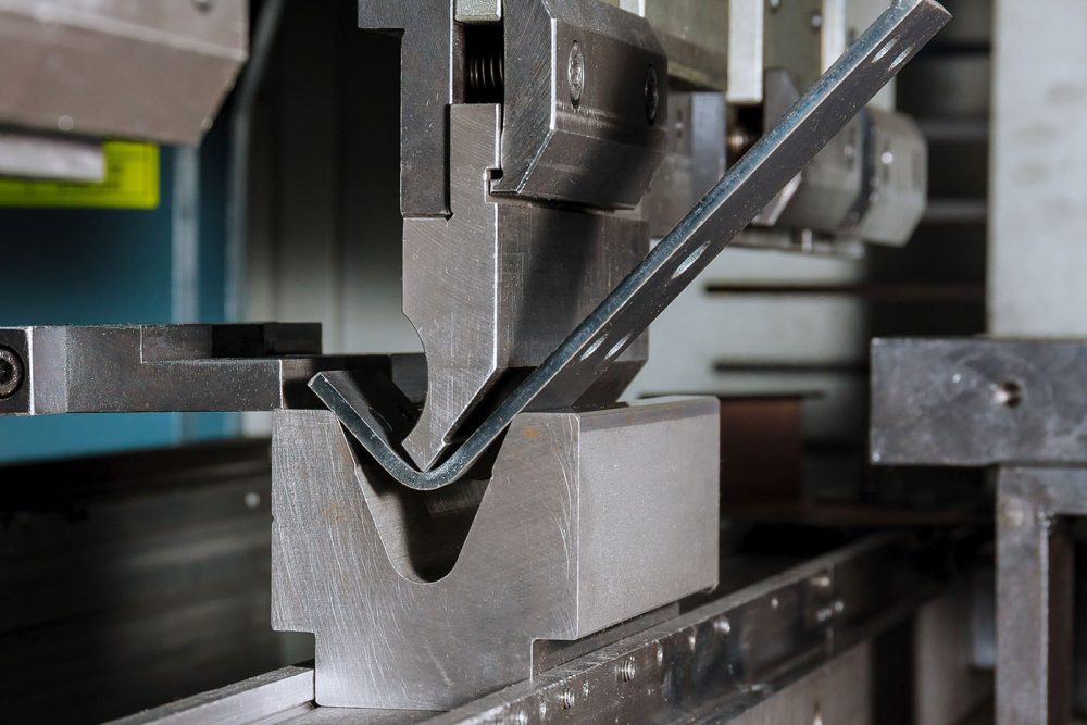 The process of bending sheet metal on a hydraulic bending machine. Metalworking plant.