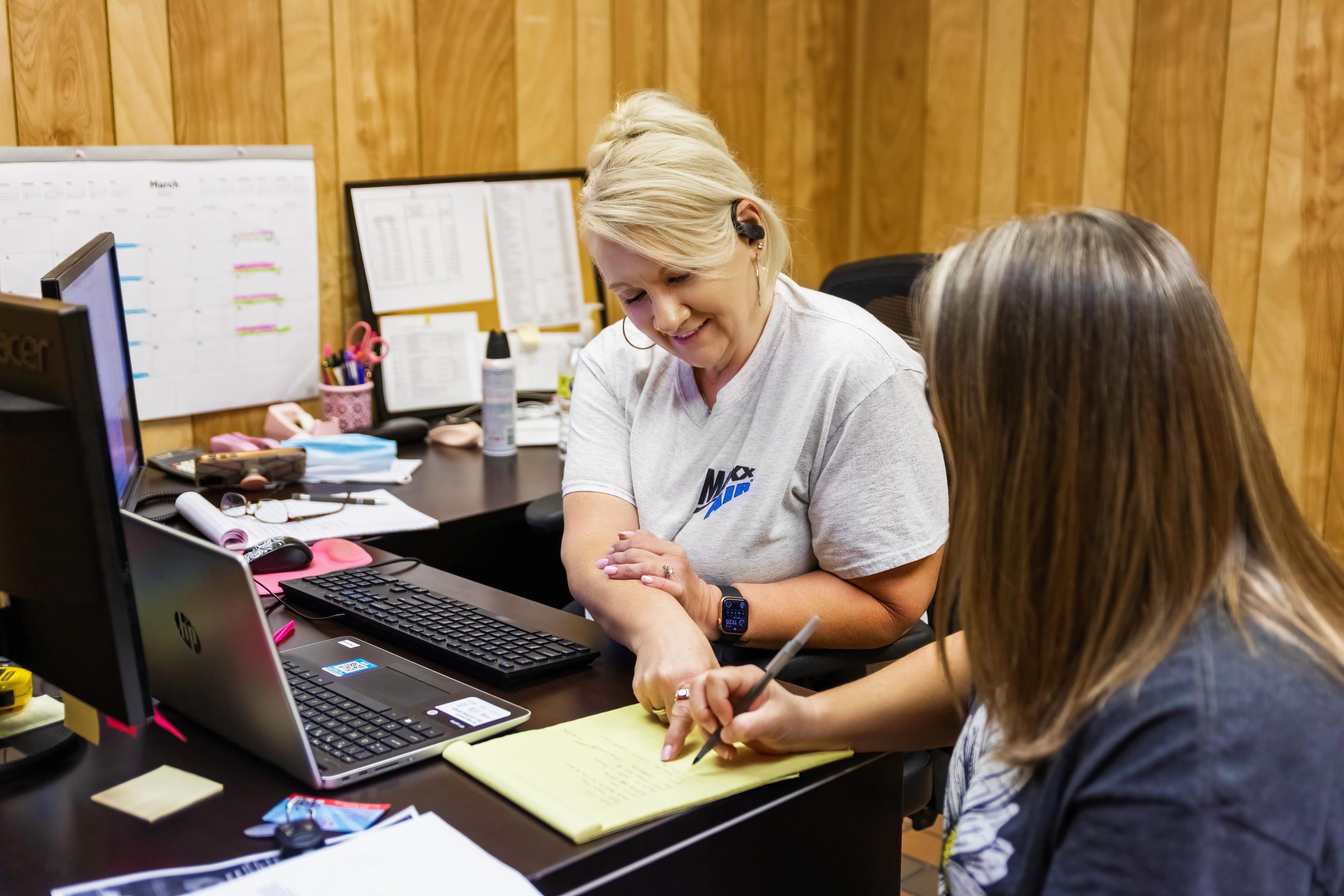 A customer service representative looks over a notepad with a customer.